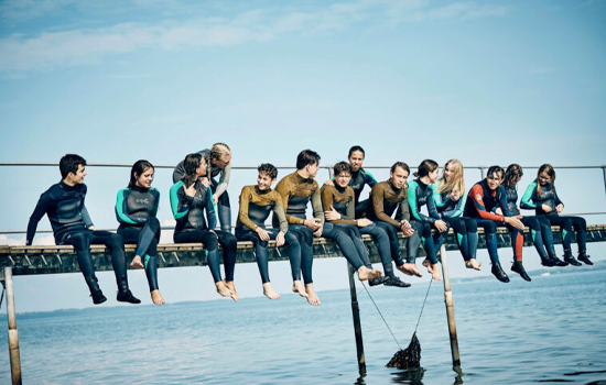 En række efterskoleelever i våddragter sidder klar til vandsport som en del af deres efterskole adventure.